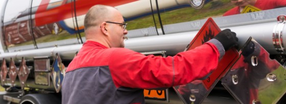 Ein ZEKU-Fahrer bringt die orangefarbene Gefahrgut-Warntafel am Tankauflieger an.